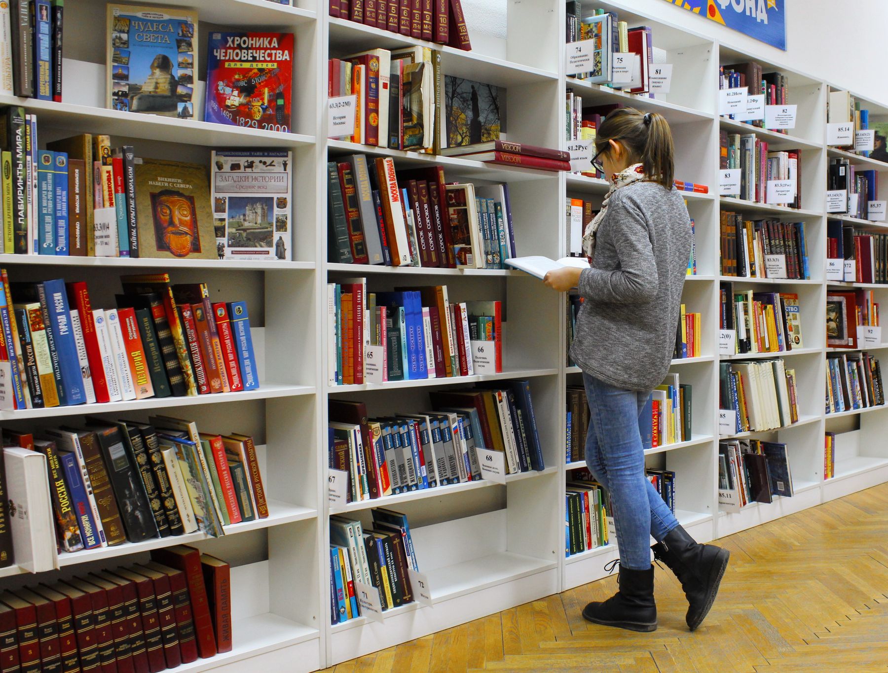 Reader among library shelves, used for the Fasthap knowledge assistant.